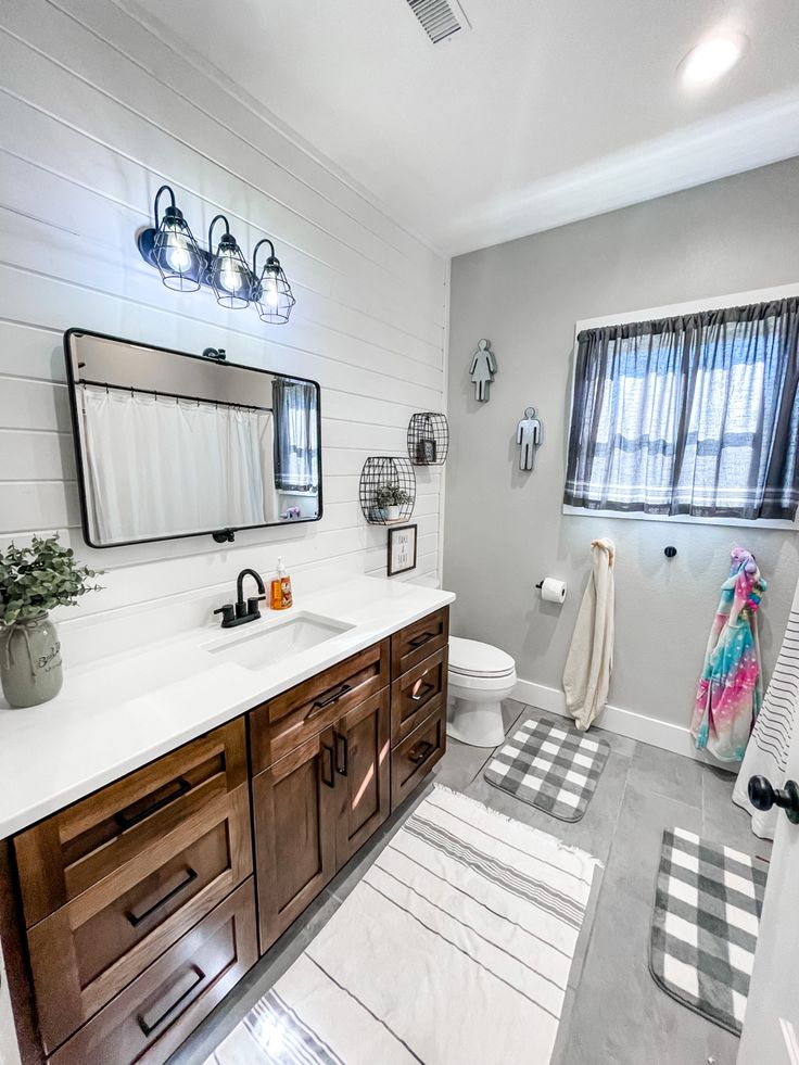 a bathroom with white walls and wood cabinetry on the vanity, along with a striped rug