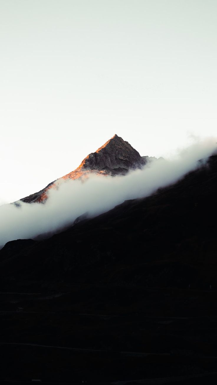 the top of a mountain is covered in clouds