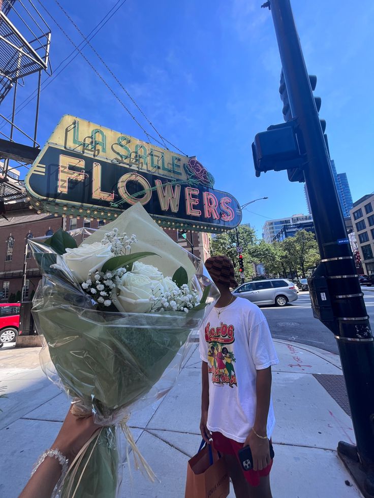 a man is standing on the sidewalk with flowers