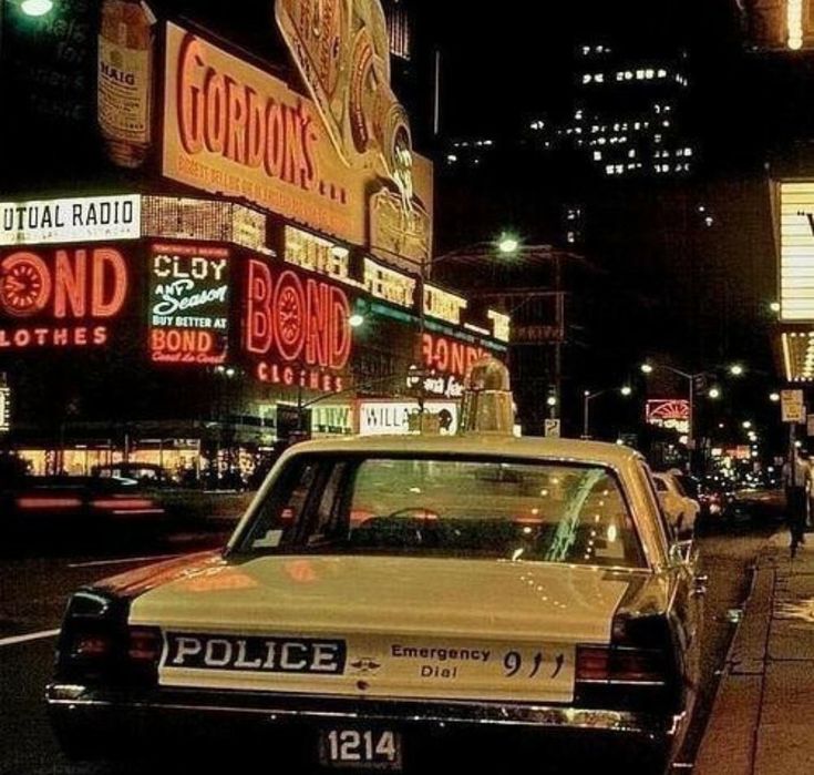 a police car is parked on the side of the road in front of neon signs