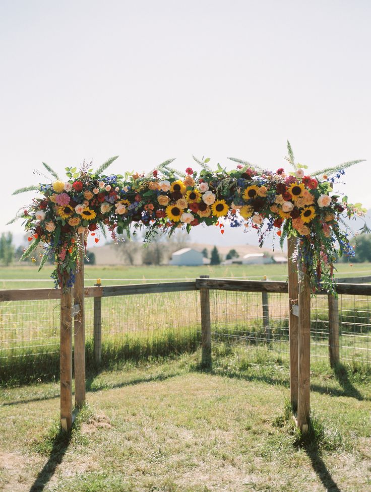 an outdoor wedding ceremony setup with sunflowers and greenery on the top of it