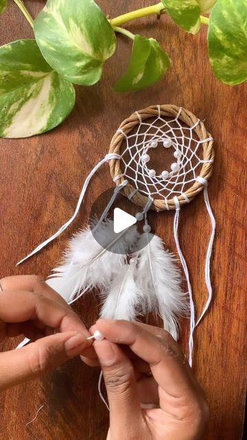 someone is making a dream catcher with feathers