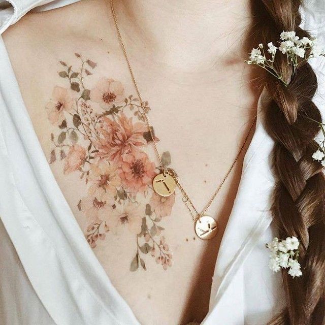 a woman wearing a white shirt with flowers on her chest and a gold disc necklace