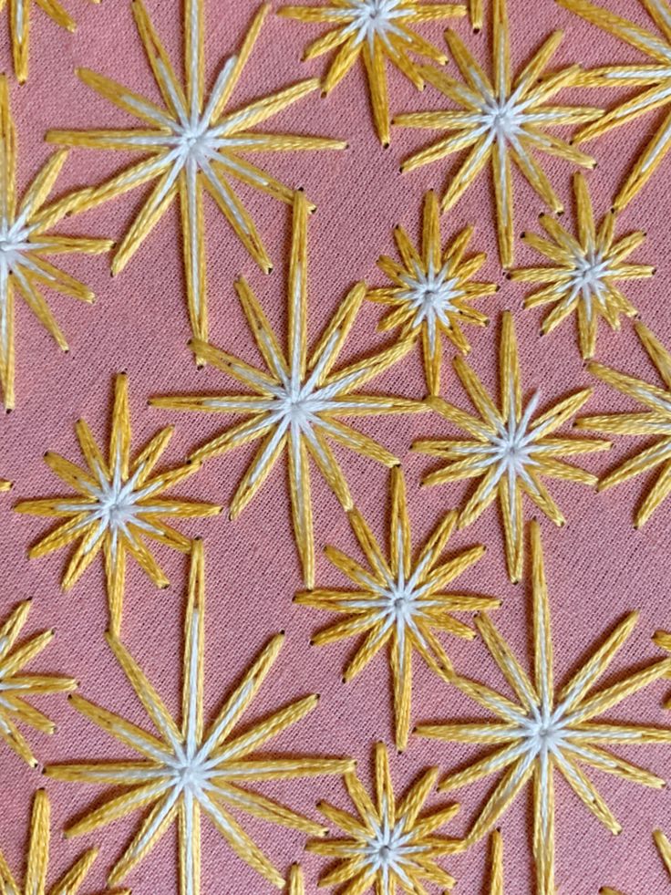 gold and white flowers on pink fabric with small stars in the center, as well as smaller ones