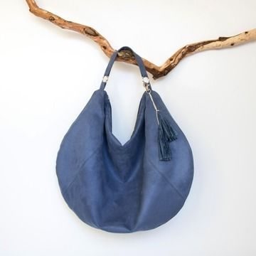 a blue leather bag hanging on a tree branch