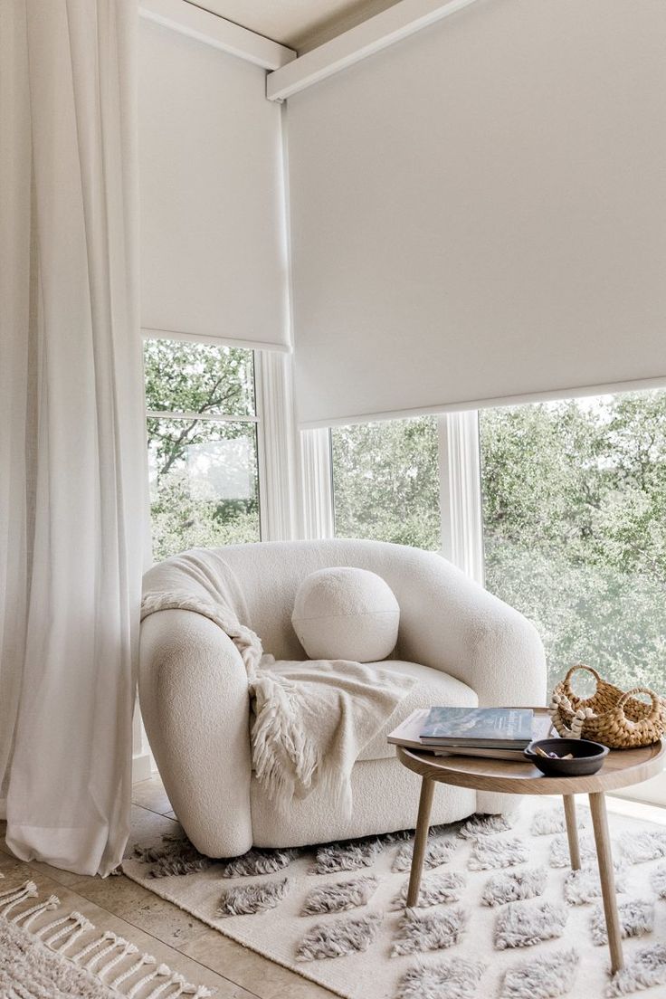 a living room with white furniture and large windows