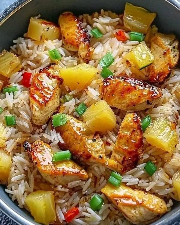 a bowl filled with rice, pineapples and chicken