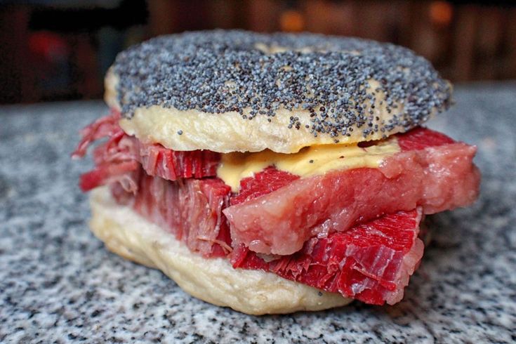 a sandwich with meat and cheese on it sitting on top of a granite countertop