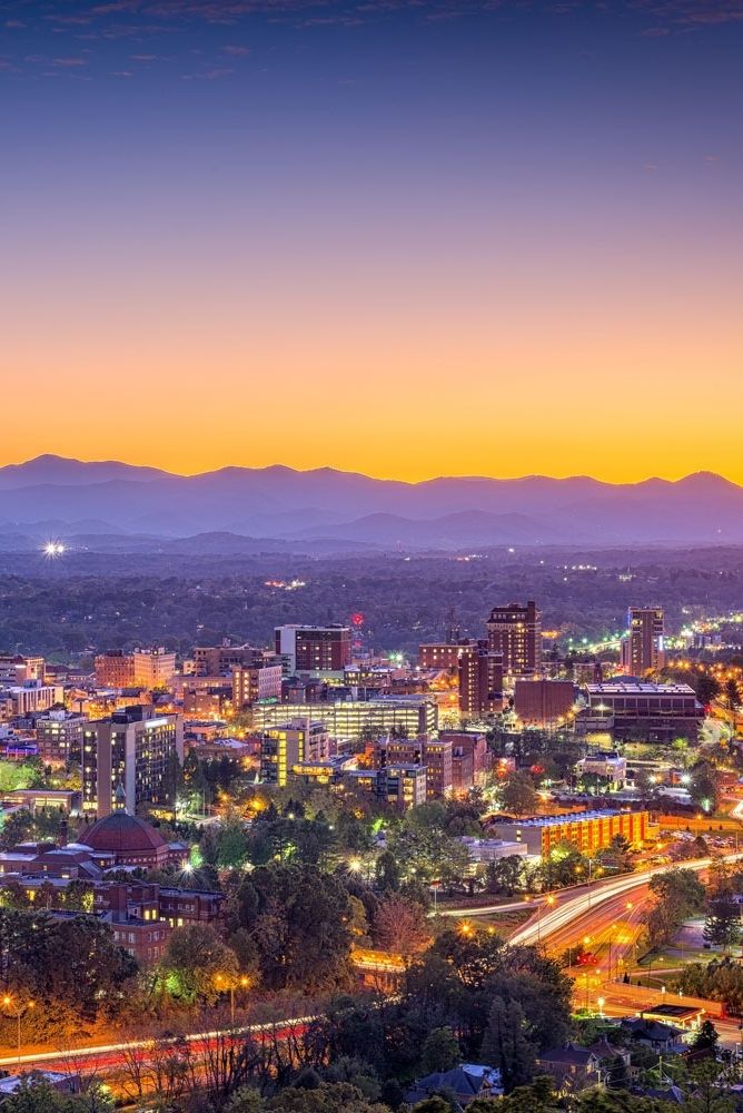 the city is lit up at night with mountains in the background