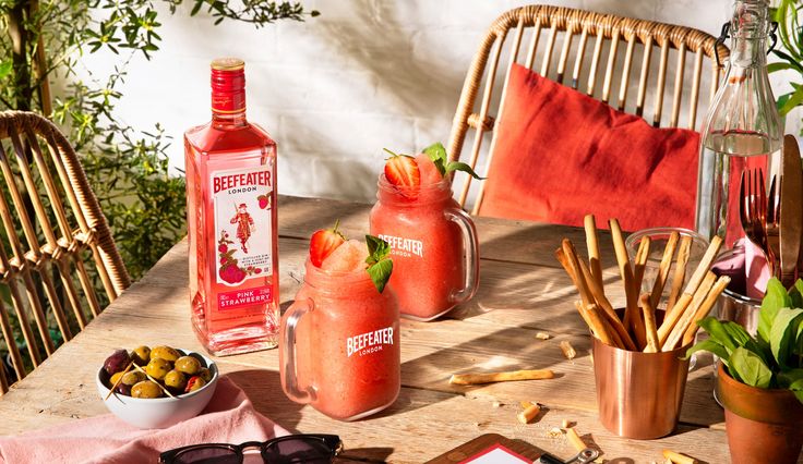 a table topped with glasses and bottles filled with liquid next to other items on top of a wooden table