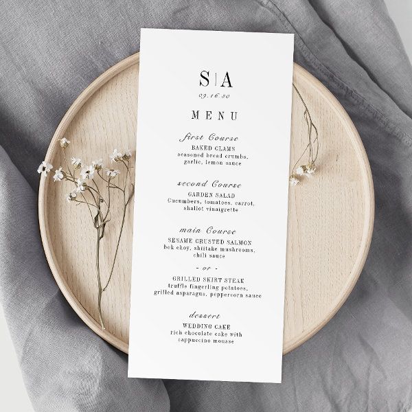 a white menu card sitting on top of a wooden plate next to a gray napkin