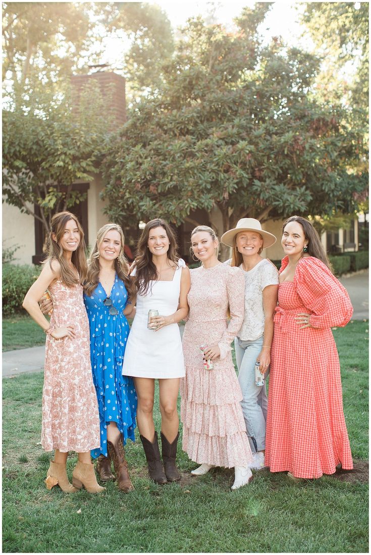 a group of women standing next to each other on top of a lush green field