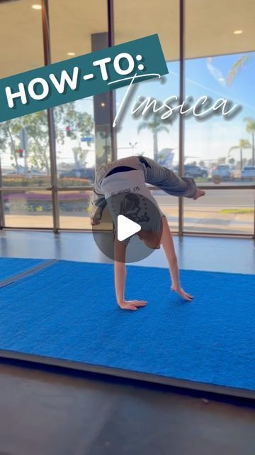 a person doing a handstand on a blue mat in front of a window