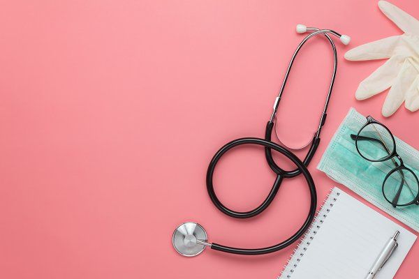 a doctor's stethoscope, eyeglasses and notepad on a pink background