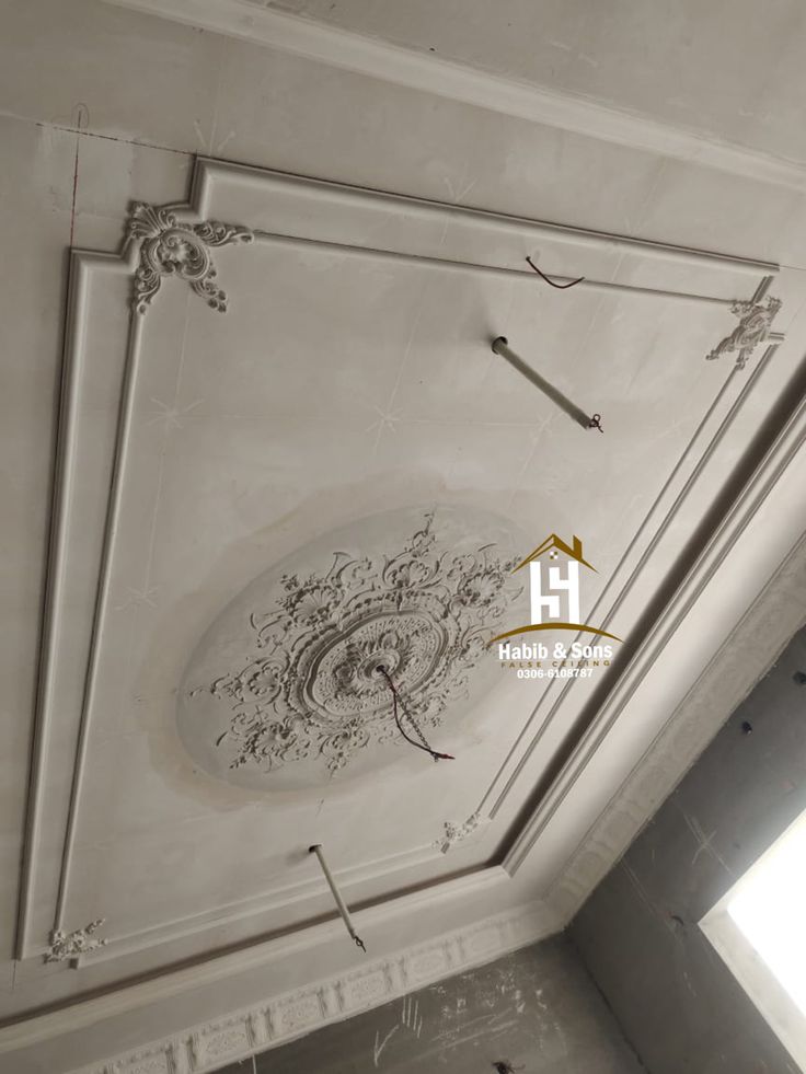 an ornate ceiling in the corner of a room with white walls and plaster work on it