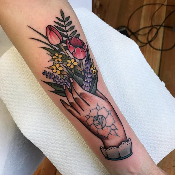 a woman's arm with flowers on it and a cupcake in the middle