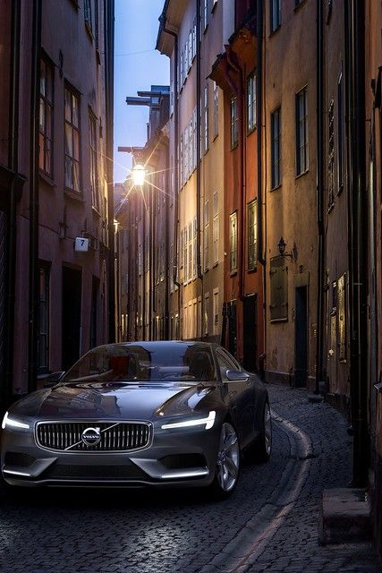 a car parked on the side of a cobblestone road in an alleyway