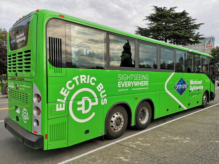 a green electric bus parked in a parking lot