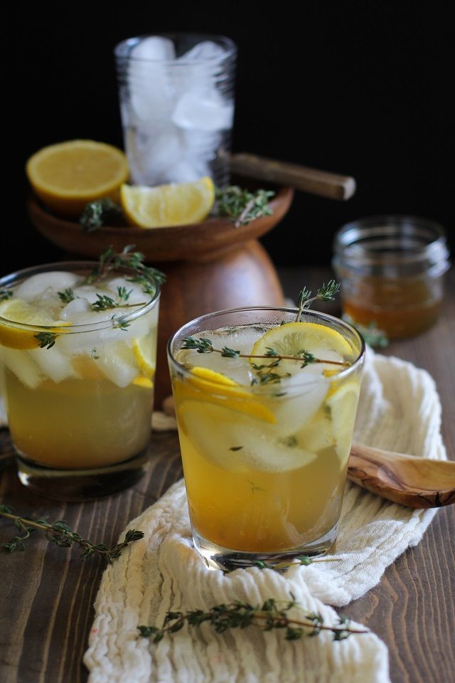 two glasses filled with lemonade sitting on top of a table next to a wooden spoon