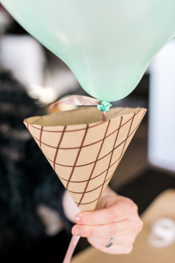 a person holding an ice cream cone with a green balloon attached to it's side