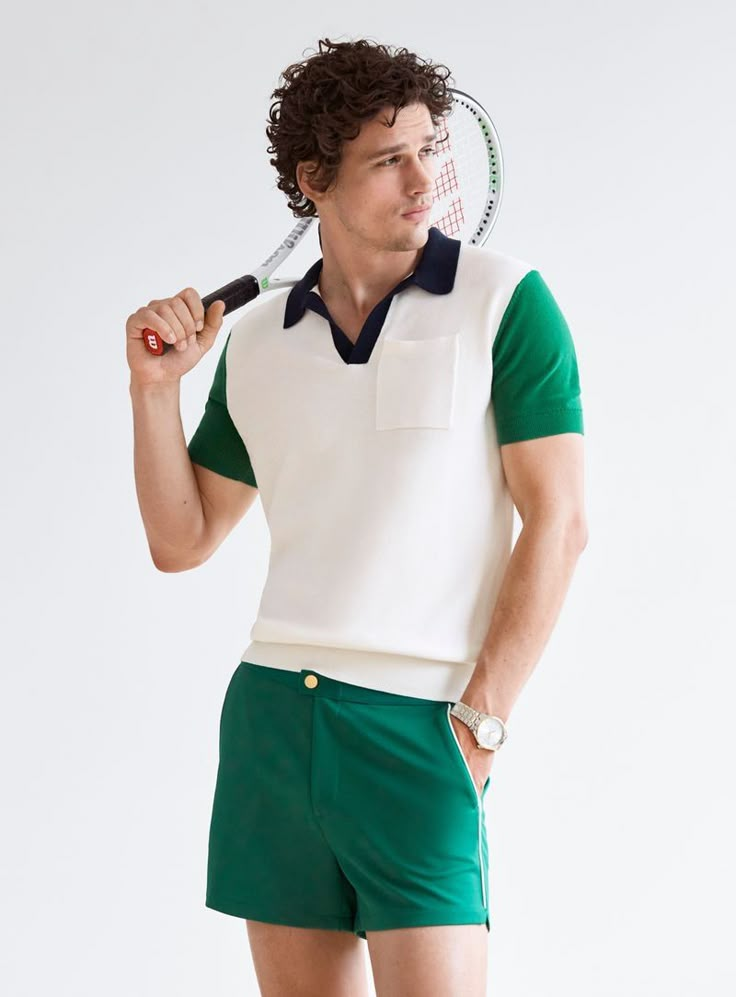 a man holding a tennis racquet in his right hand and wearing green shorts