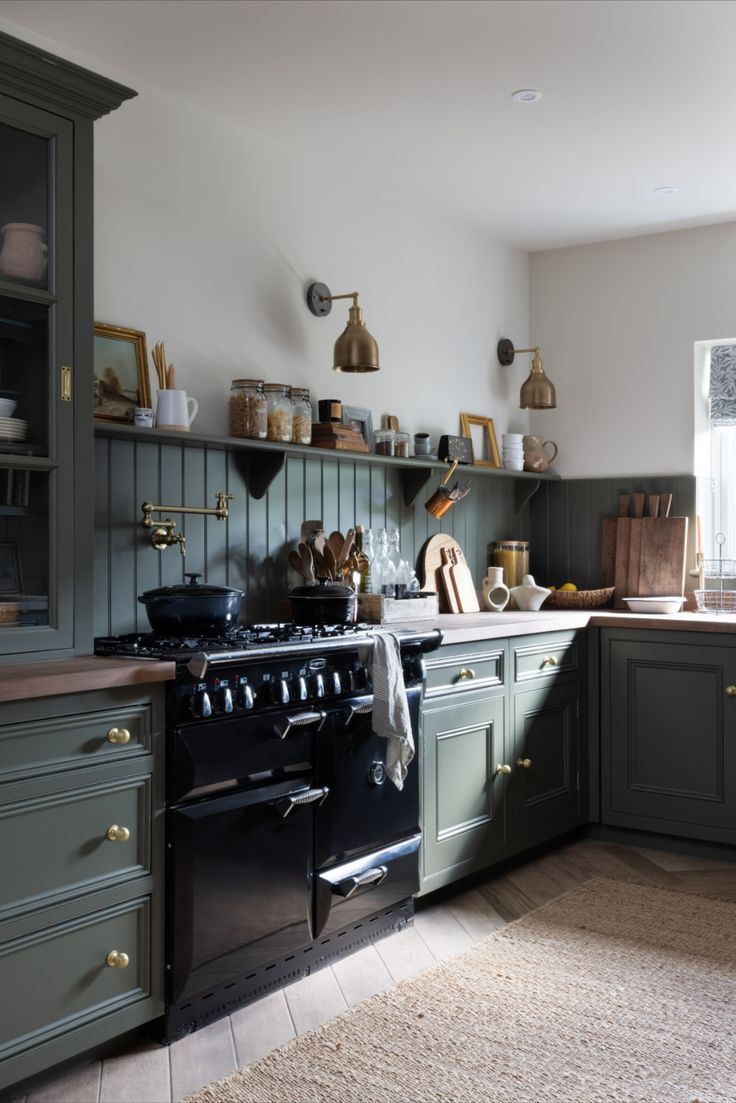 a kitchen with green cabinets and an oven in the center, along with a rug on the floor