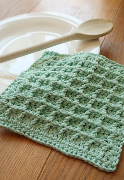 a crocheted dishcloth on a plate with a spoon