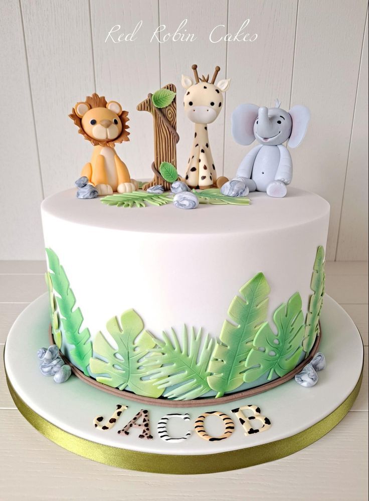 a white cake with green leaves and animals on top