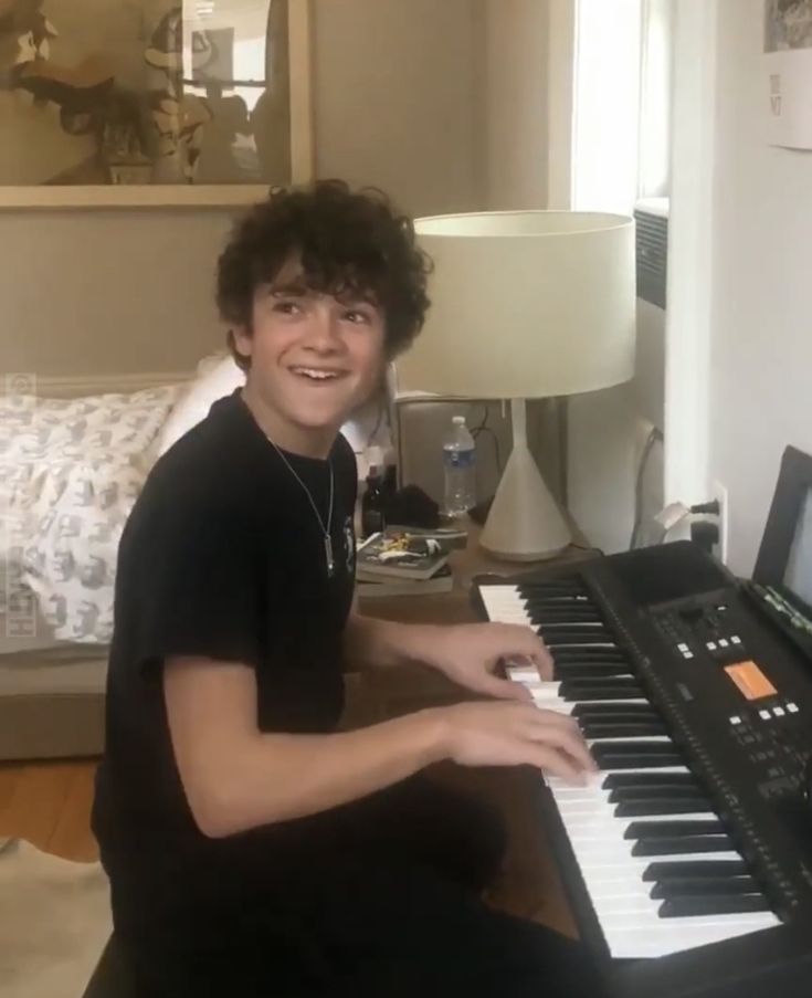 a young man sitting in front of an electronic keyboard