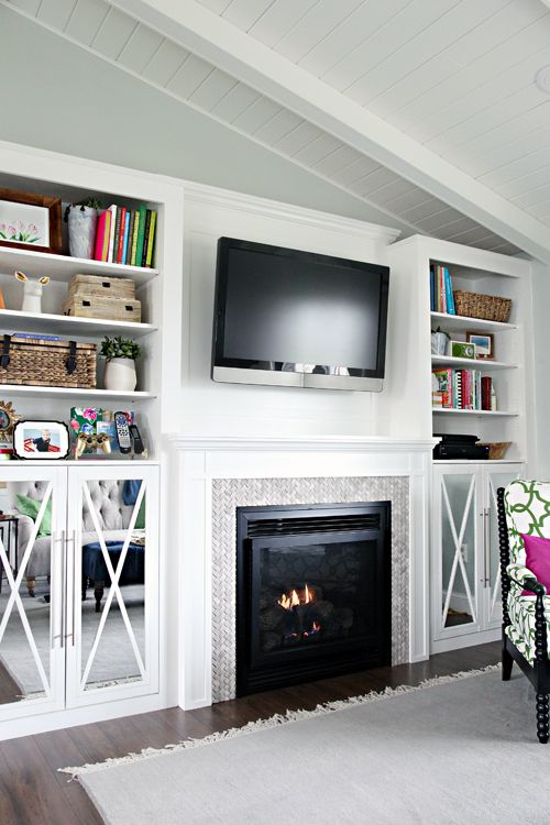 a living room with a fire place and bookshelves on either side of the fireplace