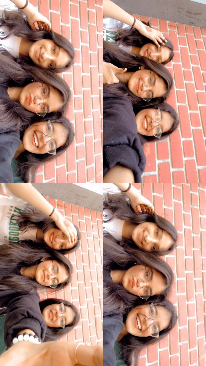 two women standing next to each other in front of a red brick wall and floor