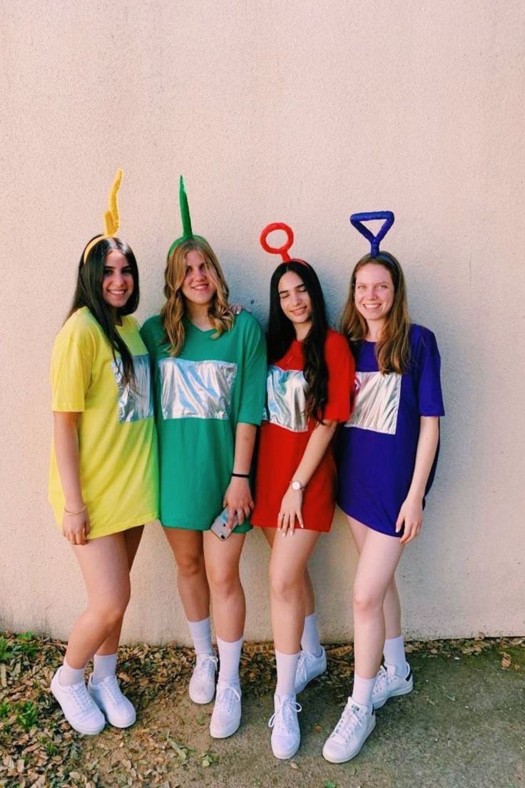 four girls are dressed up in costumes and standing next to a wall