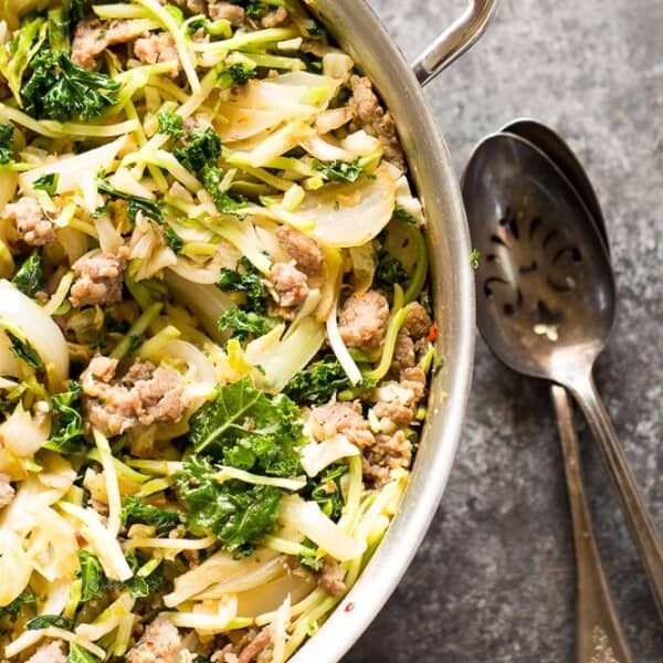 a pan filled with meat and vegetables on top of a table next to a spoon