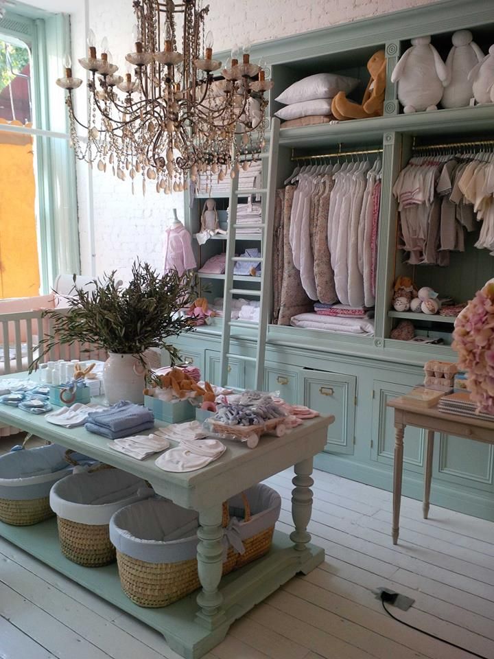 a room filled with lots of clothes and baskets on top of a wooden table next to a window