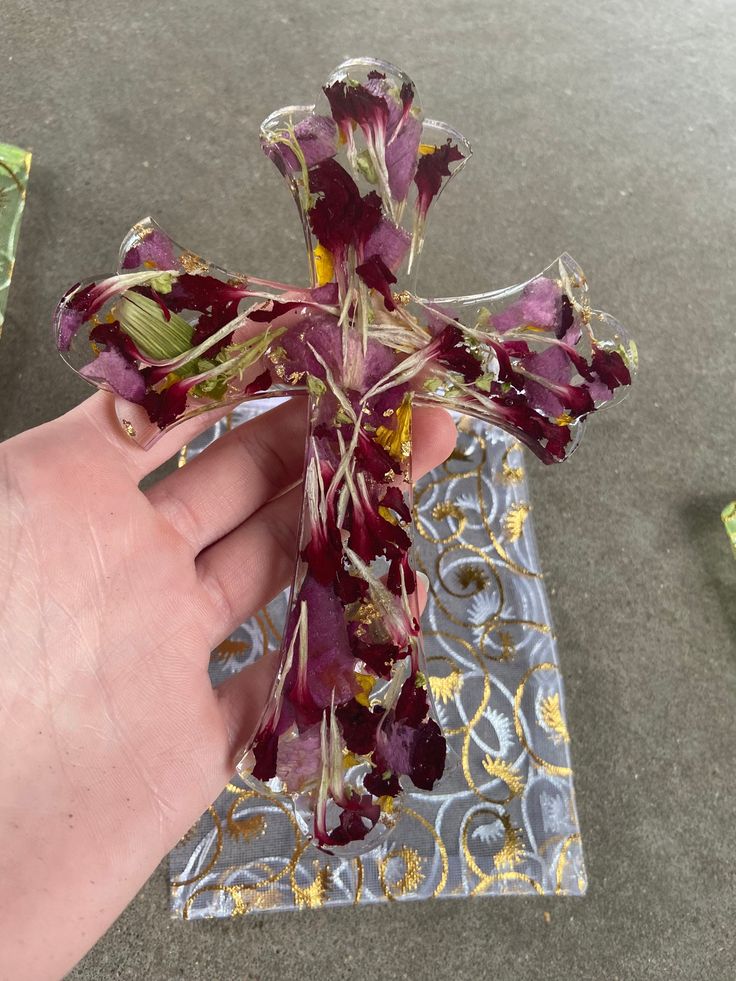 a hand holding a cross made out of dried flowers