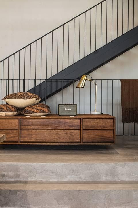 a wooden dresser sitting under a staircase next to a stair case with pillows on it