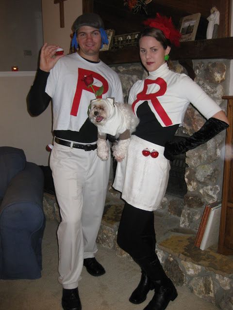 a man and woman dressed in costumes standing next to each other with a dog on their lap