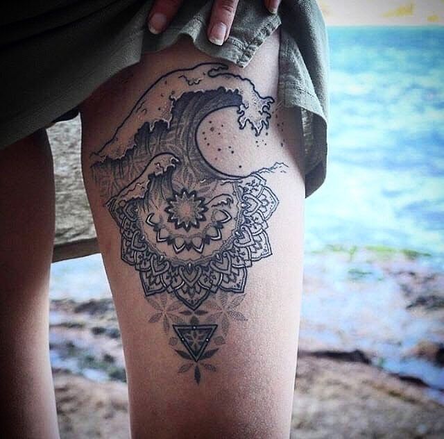 a woman's leg with a tattoo on it and an ocean in the background