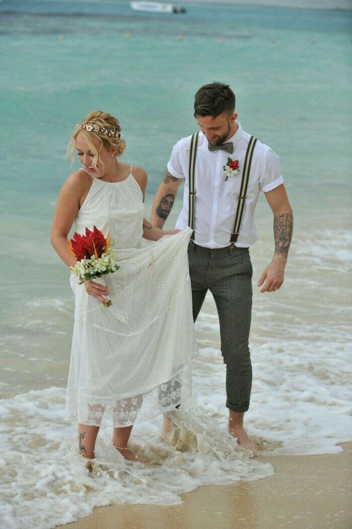 a bride and groom walking into the ocean