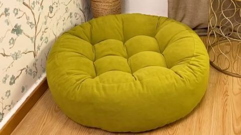 a green round chair sitting on top of a wooden floor next to a vase with flowers