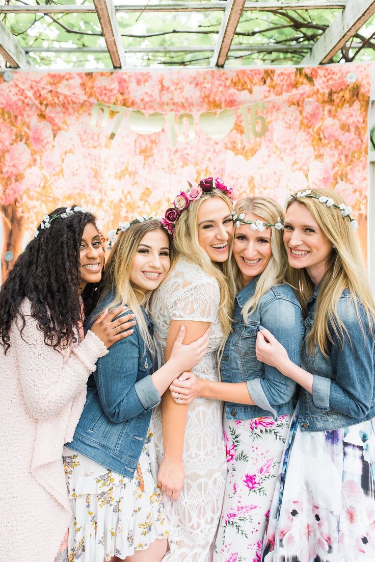 a group of women standing next to each other in front of a flower covered wall