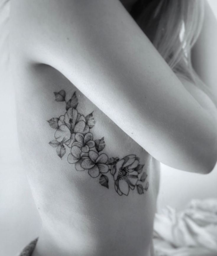 black and white photo of woman's back with flowers on it, tattoo style