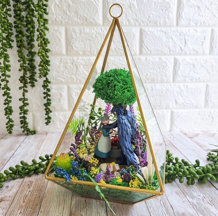 a glass vase filled with plants on top of a wooden table