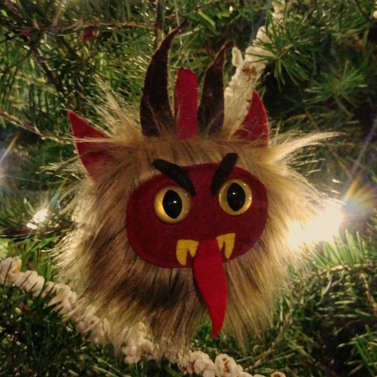 an ornament hanging from a christmas tree with feathers on it's head