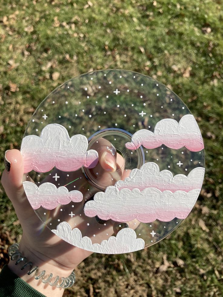 a person holding up a clear glass plate with clouds and stars in the sky on it