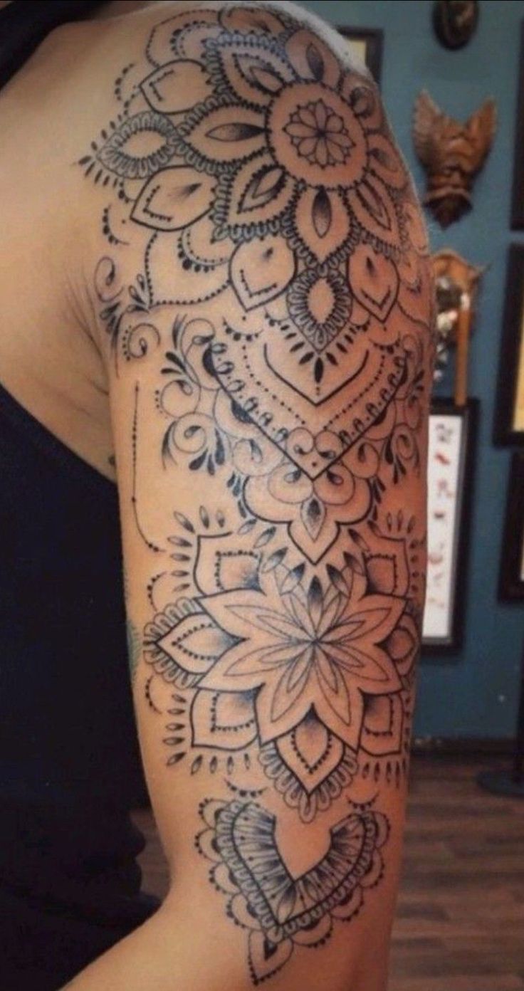 the back of a woman's arm with an intricate tattoo design on her left arm