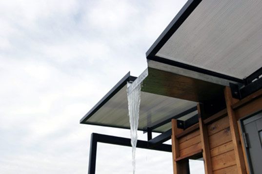 a water spout is coming from the roof of a wooden structure with a sky background