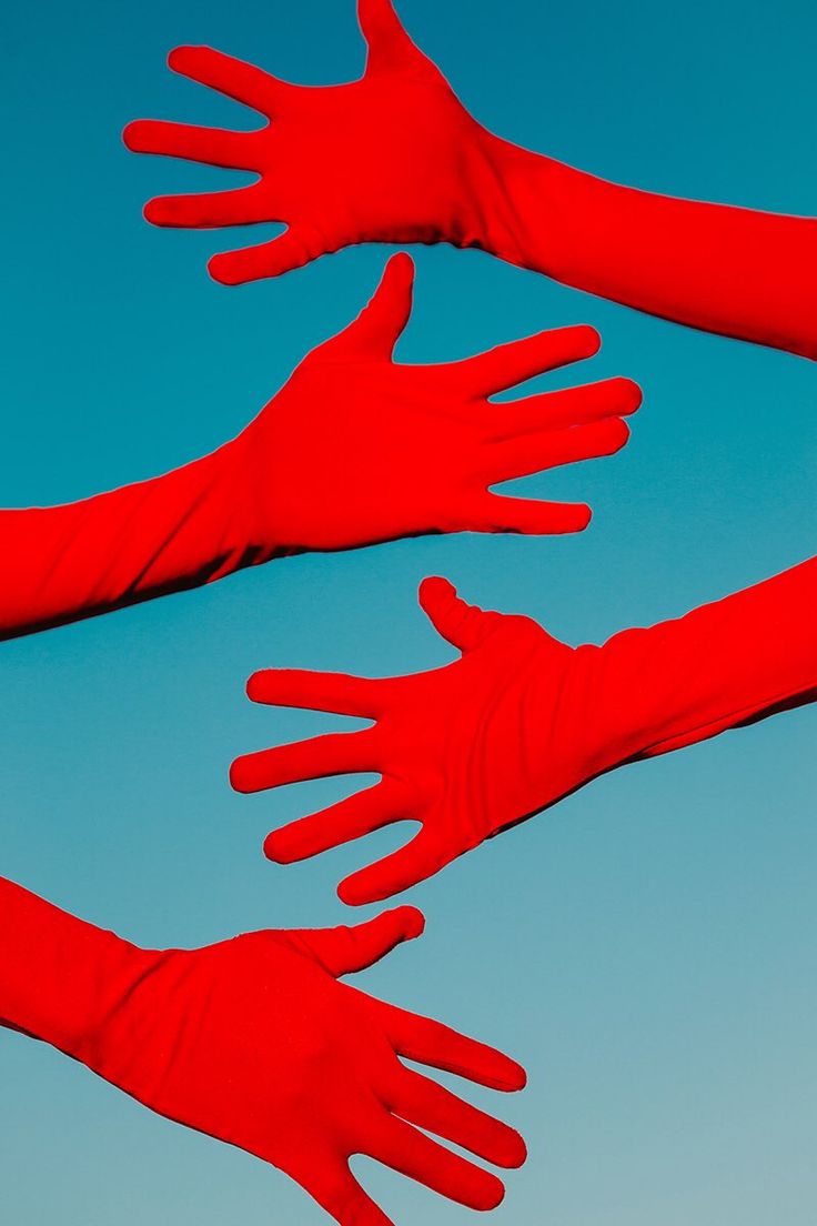 three red gloves are flying in the air with their arms extended and one hand out