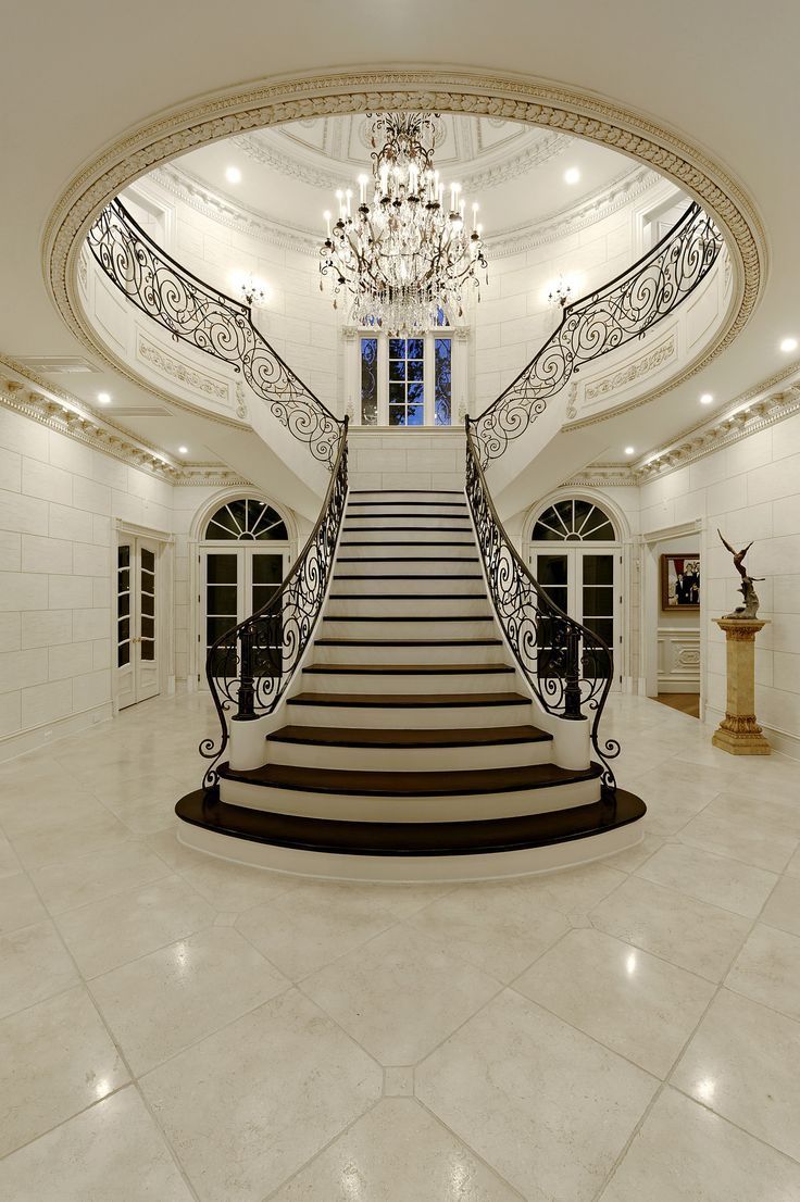 an elegant staircase with chandelier and marble flooring in a large room that has white walls