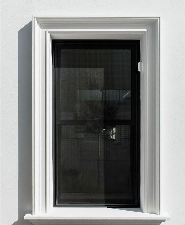 a white window sitting on the side of a wall next to a plant in a vase